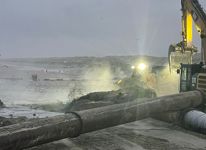 Grondwerk en kustversterking met zwaar materieel bij ruwe weersomstandigheden