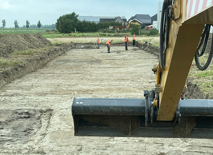 Voorbereidend grondwerk voor infrastructuurproject met graafmachine en bouwteam