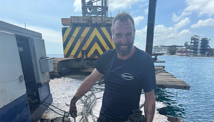 Vakman aan het werk op waterbouwkundig project met zwaar materieel aan de kust